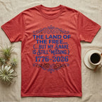 Corn Snake Still Missing Tee in Heather Red — Royal blue typographic tee reading The land of the free but my snake is still missing, with Victorian filigree and small coiled corn snakes.