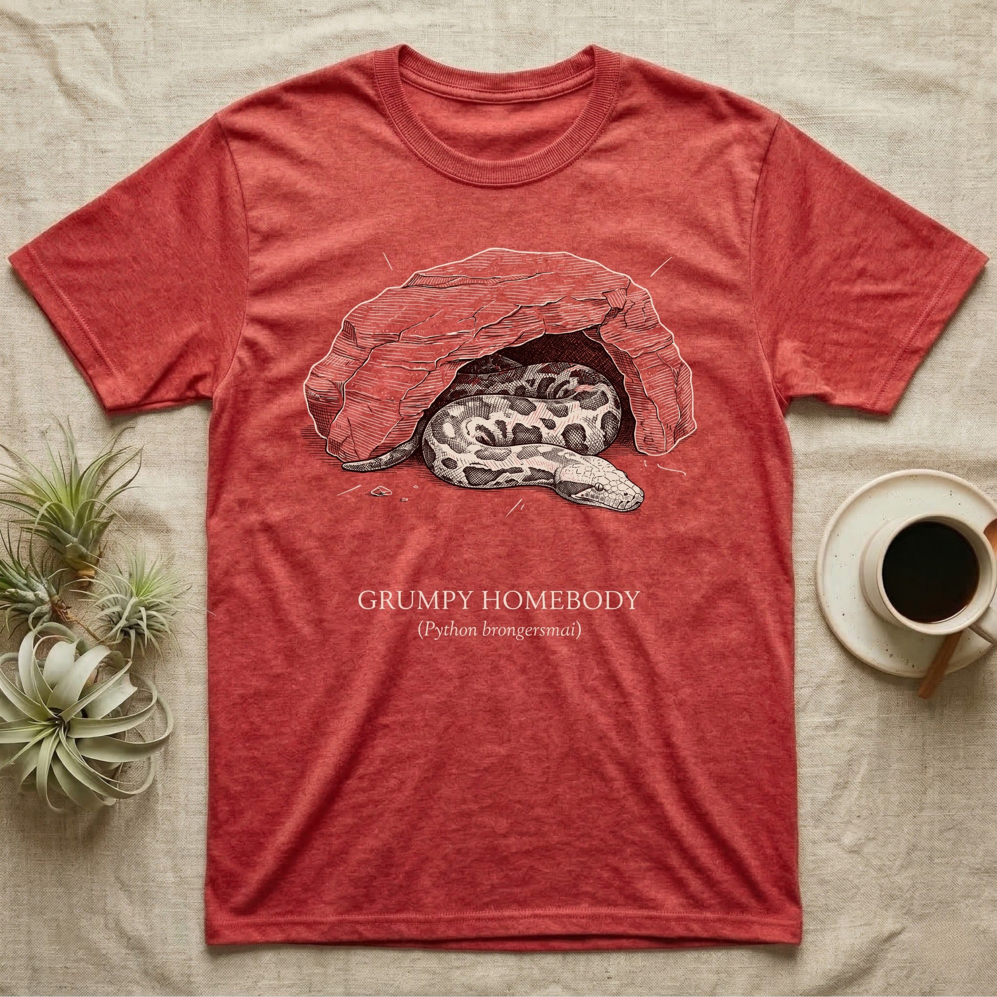 Blood Python Grumpy Homebody T-Shirt in Heather Red — Naturalist ink engraving of a blood python resting in a rock cave, captioned "Grumpy Homebody, Python brongersmai".