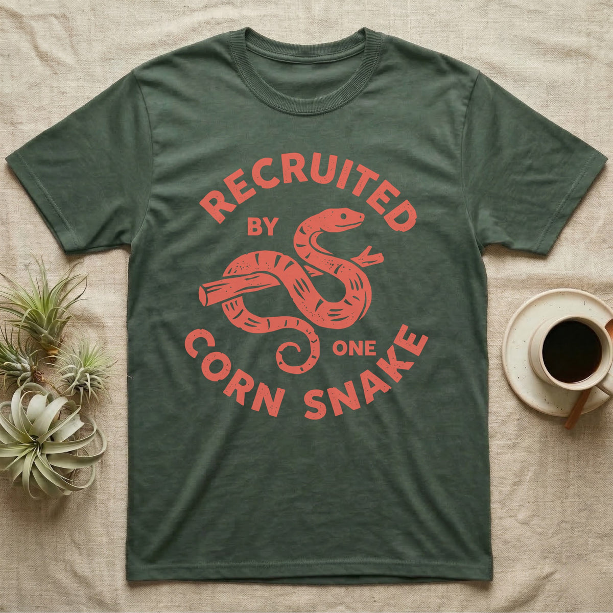 Corn Snake Recruit T-Shirt in Military Green — Hand-carved block-print badge of a corn snake on a branch inside ring lettering reading Recruited By One Corn Snake.