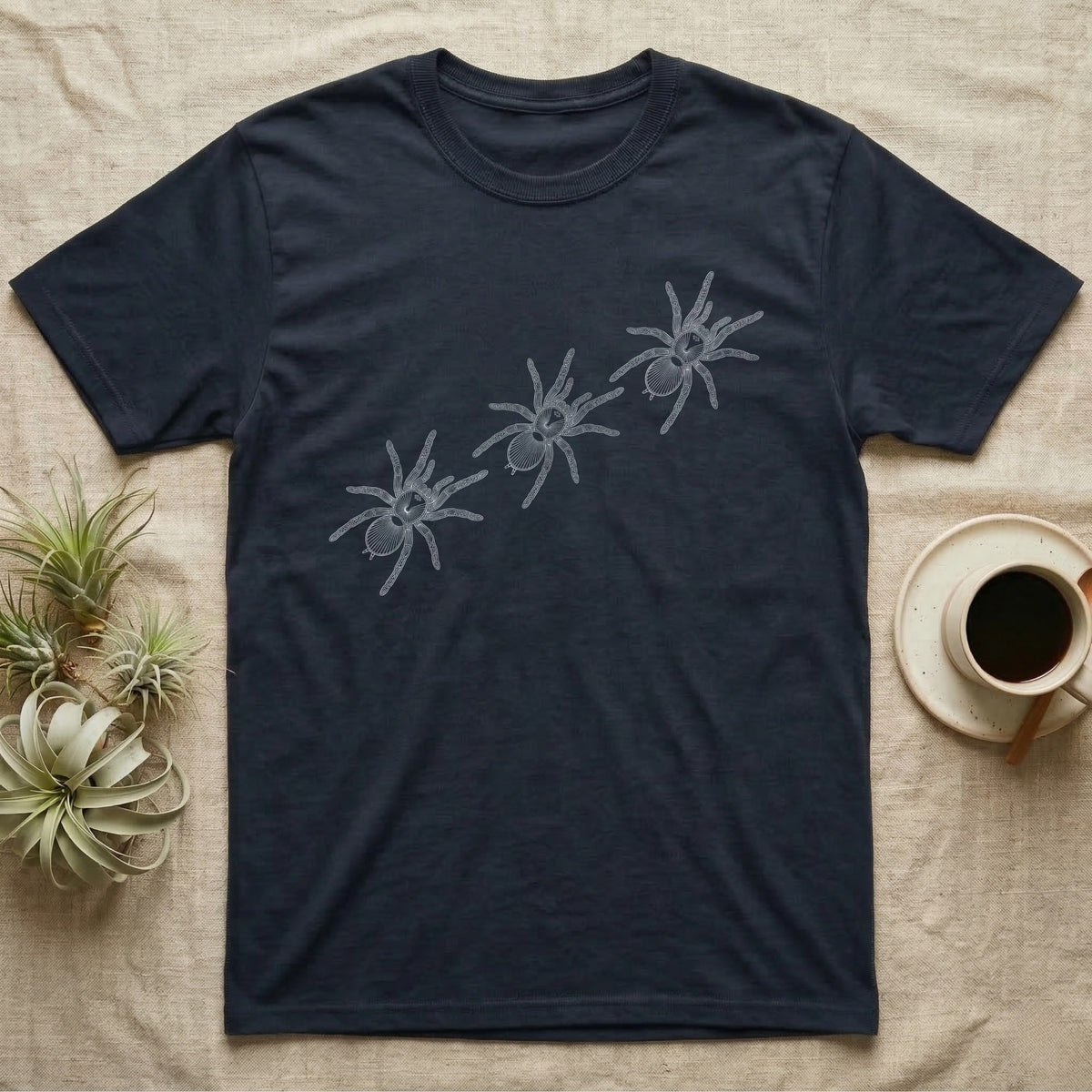 Tarantula Migration Trio T-Shirt in Navy — Three tarantulas drawn in fine pale outline, seen from above, walking on a rising diagonal across flat grey.