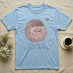 Hedgehog Do Not Unball Tee in Light Blue — Naive-doodle hand-drawn hedgehog curled in a tight defensive ball above a wobble-handwritten "Do Not Unball" label.