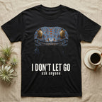 Deadpan close-up mugshot of a blue-grey tokay gecko on black, captioned I don't let go, ask anyone. — shown on a Black tee.
