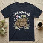 Cane Toad Baby T-Shirt in Navy — Warty cane toad among pastel toadstools and lily pads under puffy cream bubble text "just a potato".