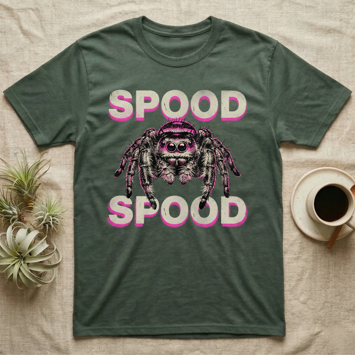Spood Jumping Spider T-Shirt in Military Green — Grunge-punk illustration of an oversized front-facing jumping spider with a distressed "Spood" wordmark in bone and acid pink.