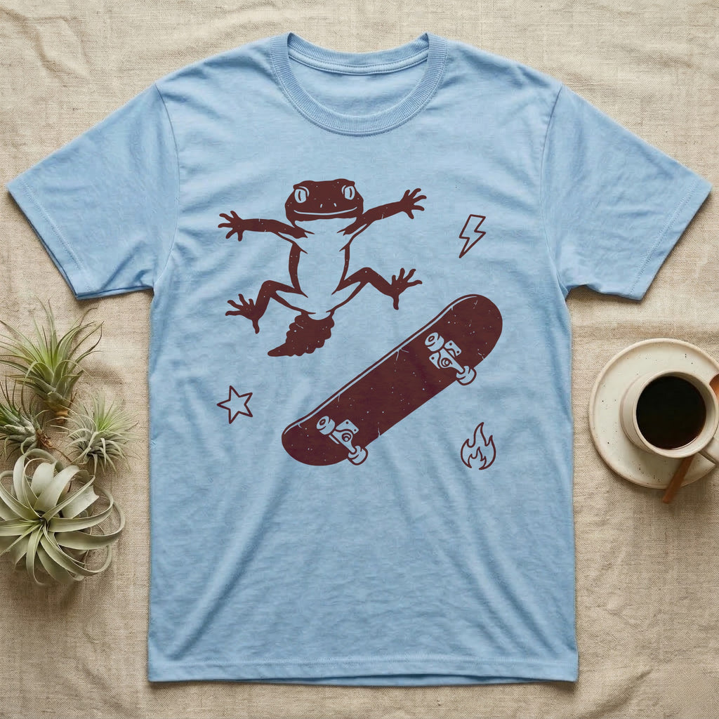 Knob-Tailed Gecko Kickflip T-Shirt in Light Blue — Distressed one-ink illustration of a knob-tailed gecko airborne mid-kickflip above a tumbling skateboard.