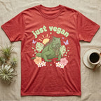 Green Iguana Baby T-Shirt in Heather Red — Green iguana with spiky crest and dewlap among pastel leaves and flowers under puffy green bubble text "just vegan".