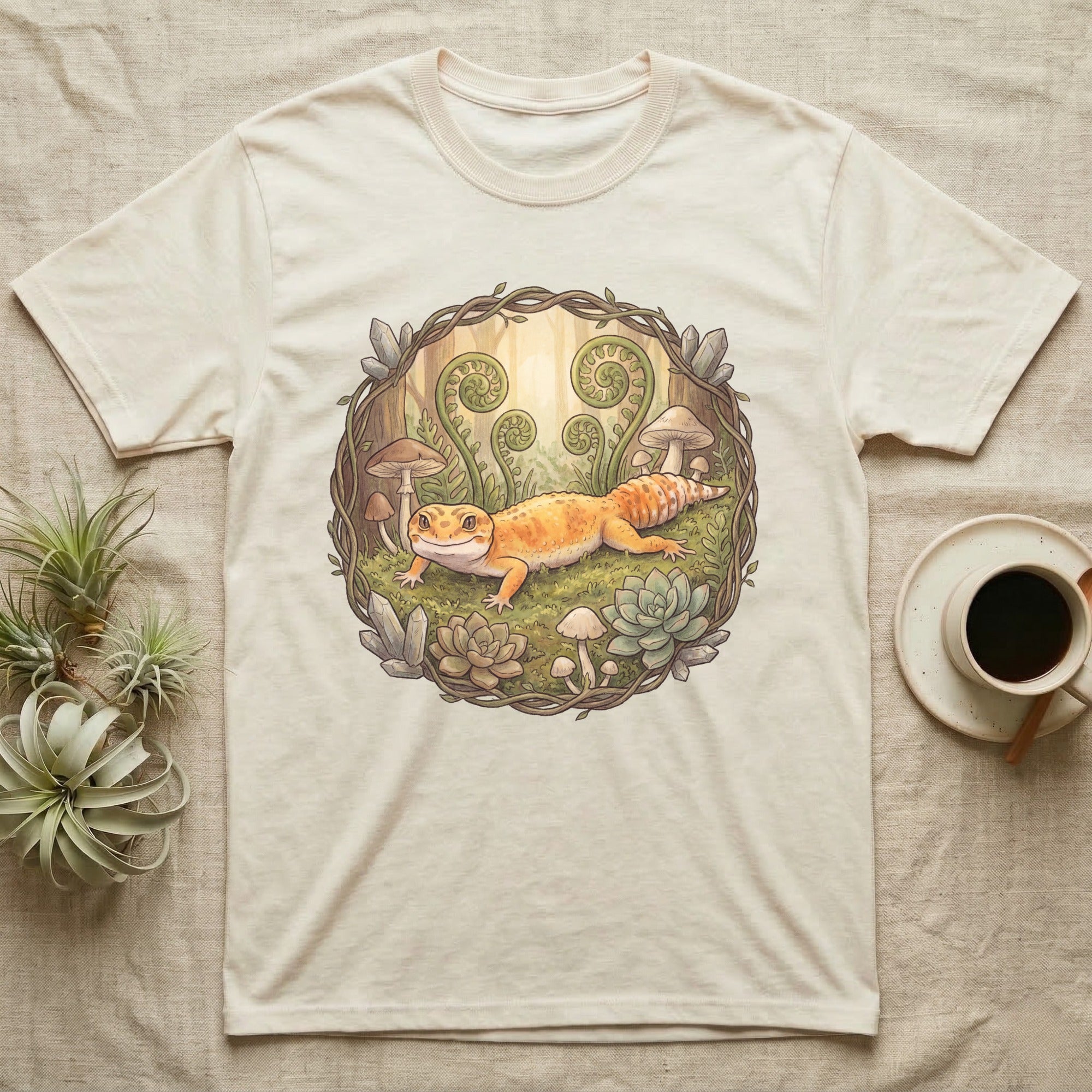Cream t-shirt with a cartoon gecko and forest elements illustration.
