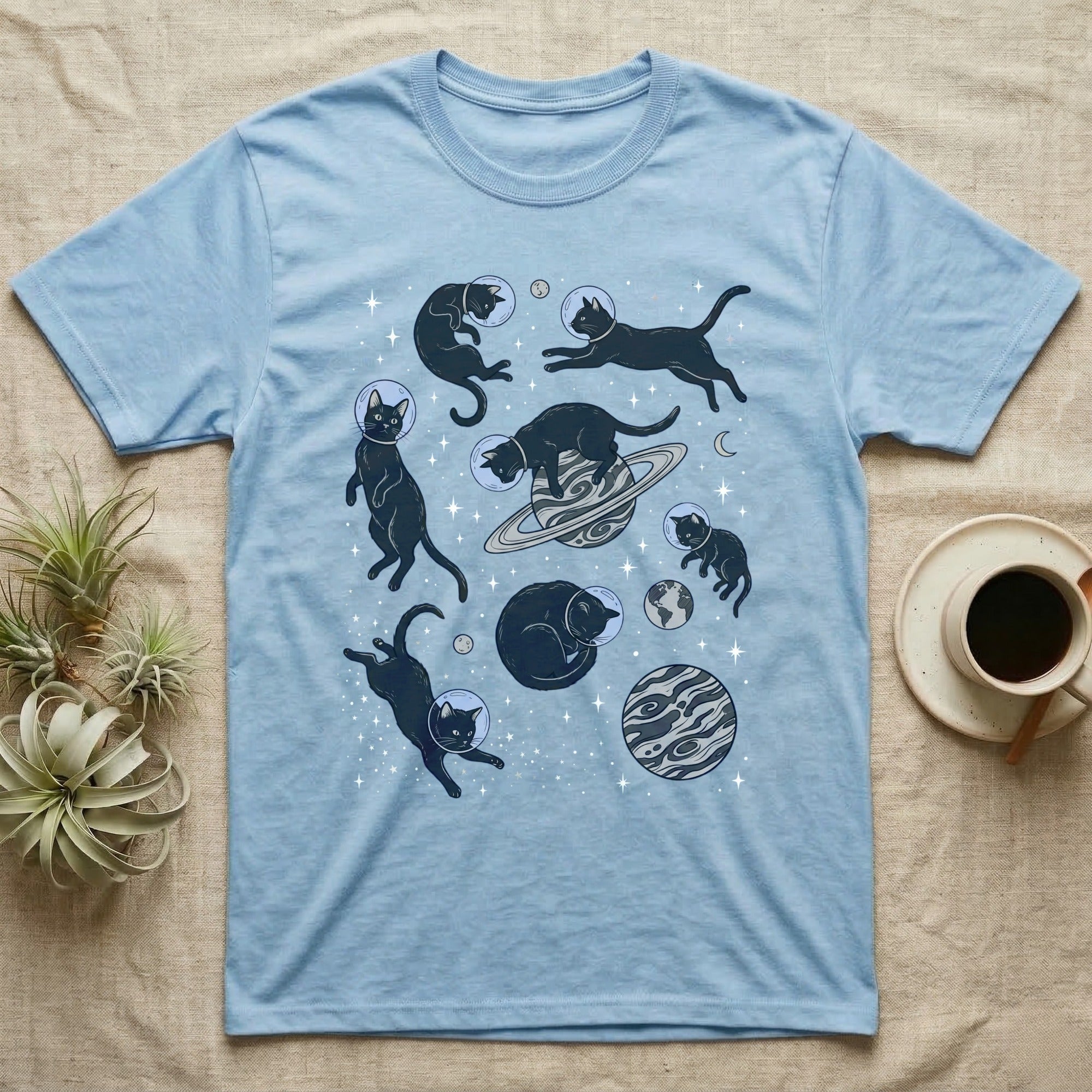 Light blue t-shirt with black cats in space with planets and stars.