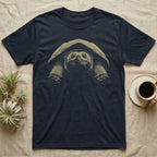 Snapping Turtle Stare T-Shirt in Navy — Single-ink common snapping turtle seen head-on under its shell, lit from above, staring at the viewer on black.
