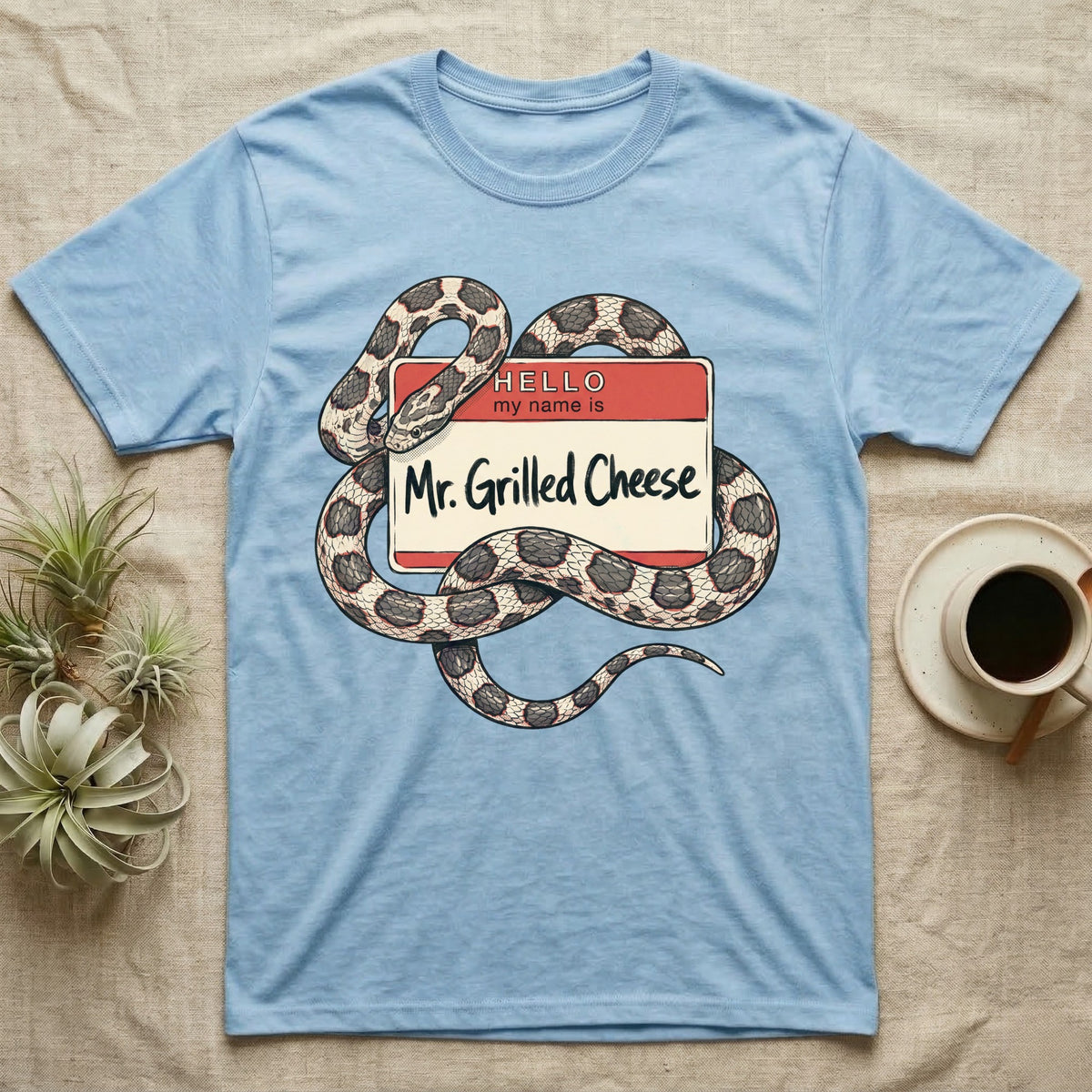 Grilled Cheese Corn Snake T-Shirt in Light Blue — Flat retro illustration of a corn snake coiled through a "Hello my name is Mr. Grilled Cheese" name-tag badge.