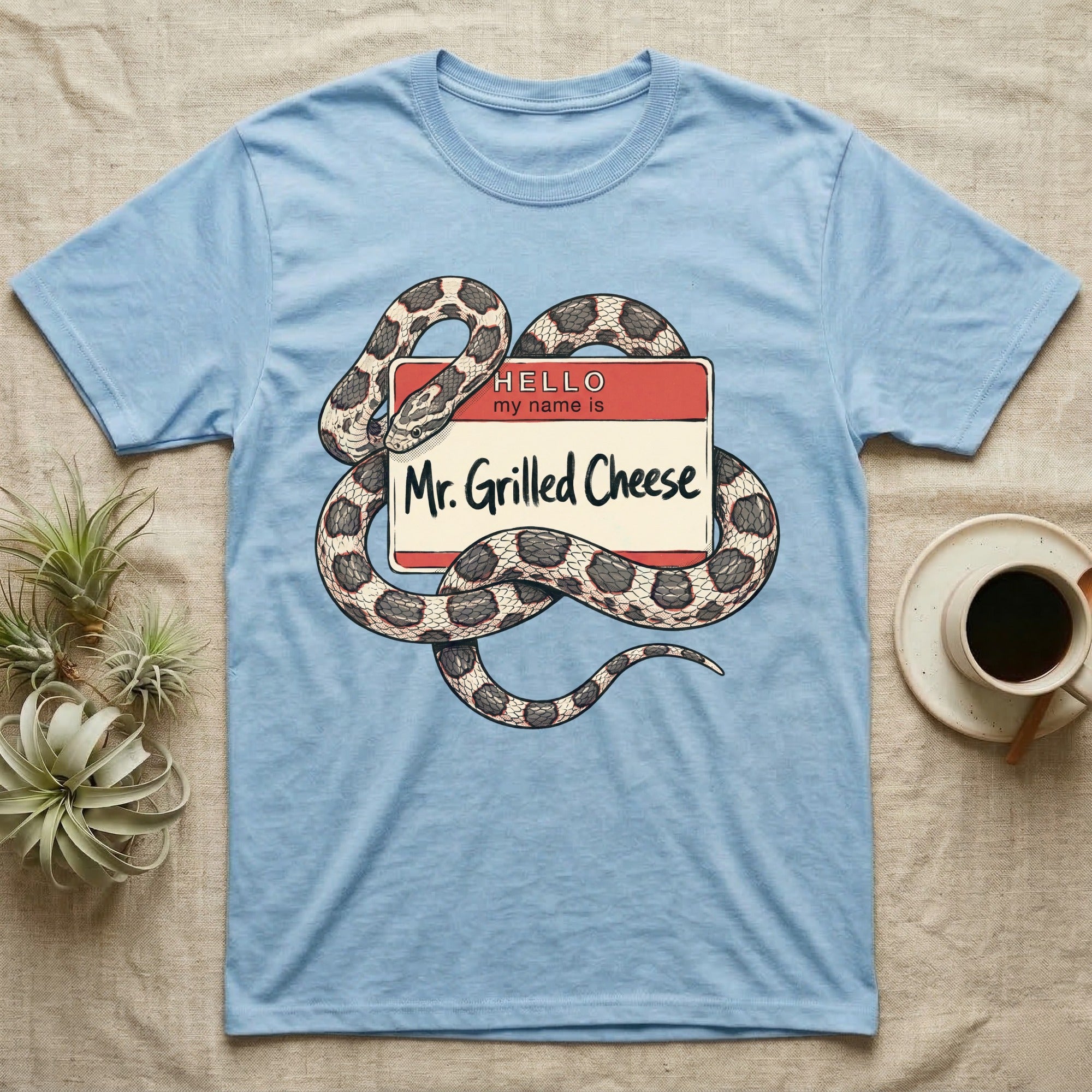 Grilled Cheese Corn Snake T-Shirt in Light Blue — Flat retro illustration of a corn snake coiled through a "Hello my name is Mr. Grilled Cheese" name-tag badge.