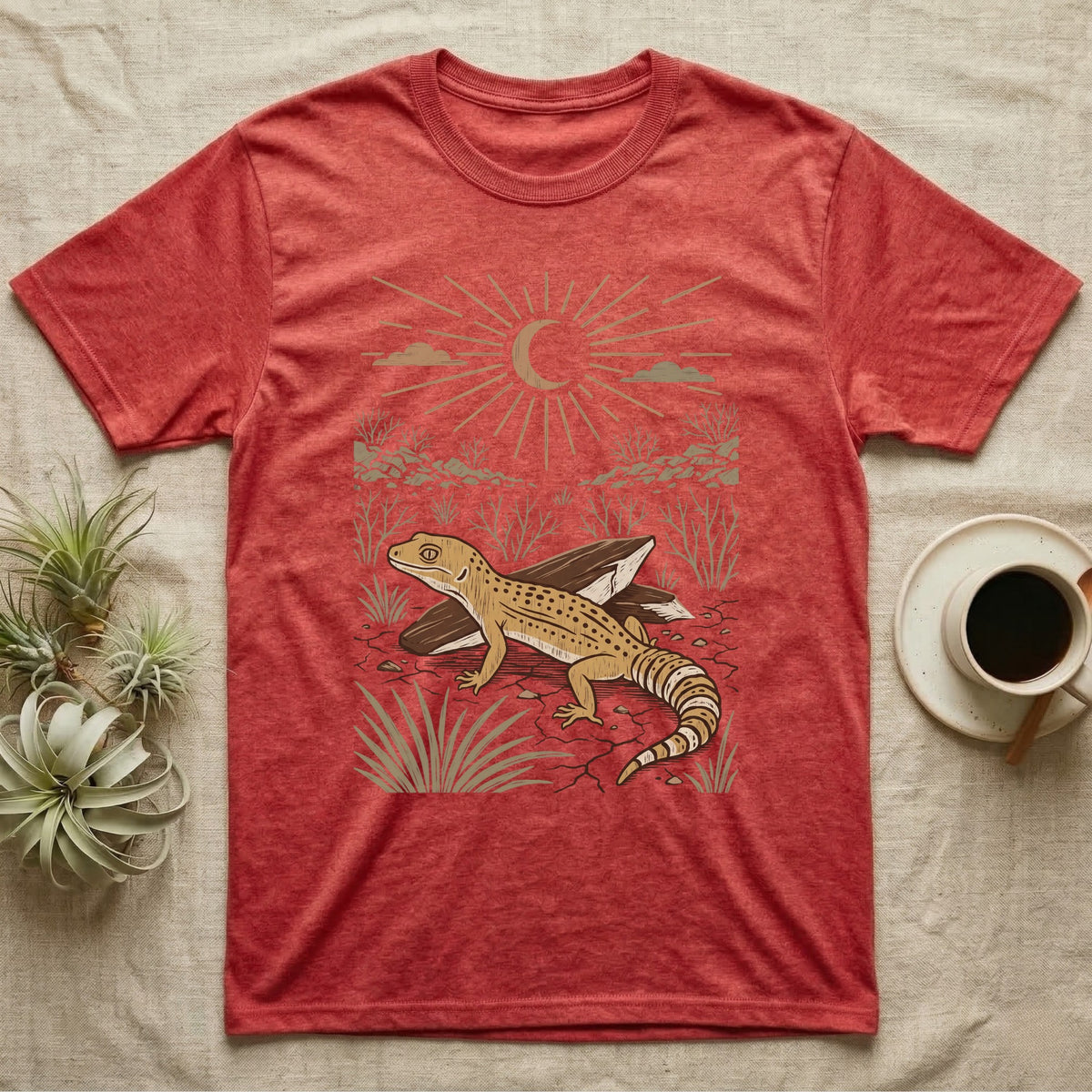 Leopard Gecko Home Range T-Shirt in Heather Red — Woodcut-style illustration of a leopard gecko standing on cracked earth beside flat stones with thorn scrub behind, no on-shirt text.