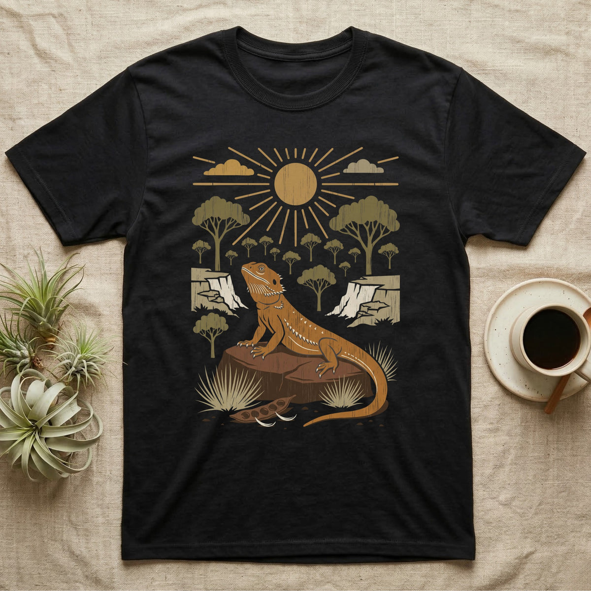Bearded Dragon Home Range T-Shirt in Black — Woodcut-style illustration of a bearded dragon basking on a boulder under a full sun with arid scrub trees and escarpments behind, no on-shirt text.