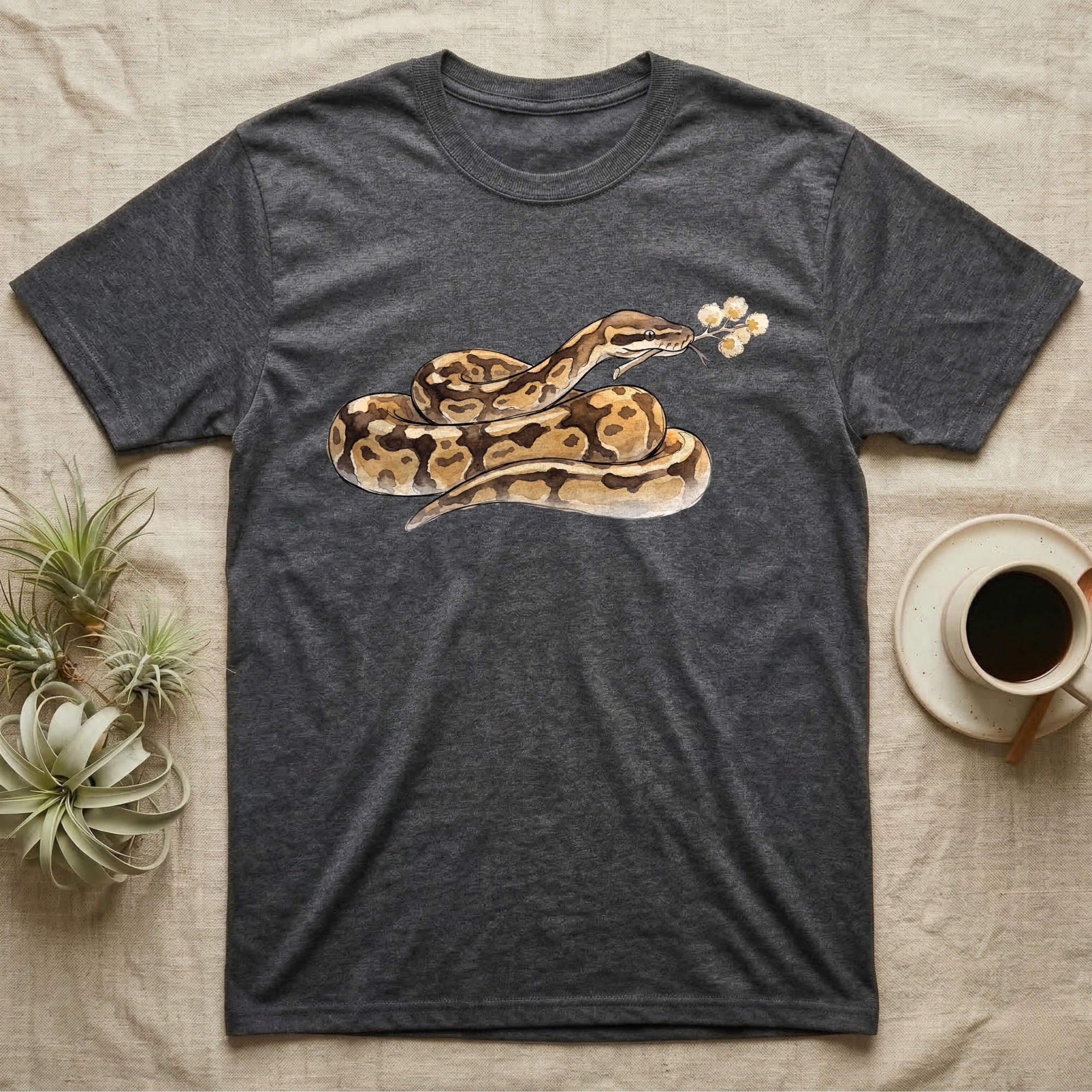 Ball Python Blossom T-Shirt in Dark Heather — Watercolor illustration of a tan-and-brown ball python holding an acacia blossom sprig, on a dark grey t-shirt.