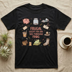 Glass Frog Frugal T-Shirt in Black — Cartoon glass frog on a leaf under the words Frugal except for one see-through frog, ringed by a piggy bank, coin jar, coupons and other thrifty things