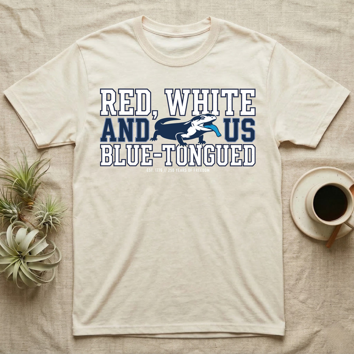 Blue-Tongued Skink 1776 T-Shirt in Natural — Navy and white blue-tongued skink with tongue out between collegiate text reading Red, White and US Blue-Tongued.