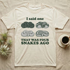 Ball Python Collector T-Shirt in Natural — Four engraved ball python morphs in tight coils between the words I said one and THAT WAS FOUR SNAKES AGO.