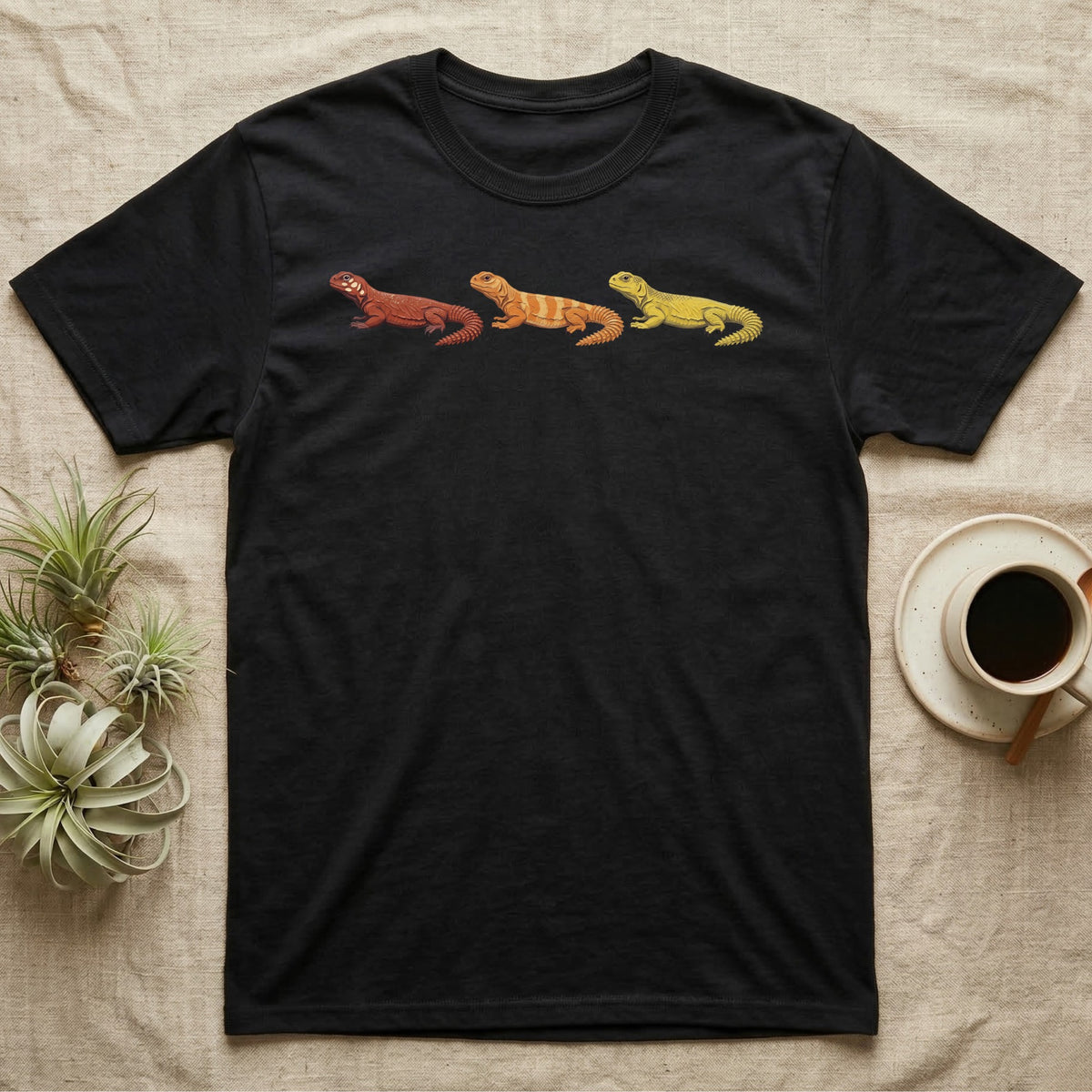 Uromastyx Colour Morph Trio T-Shirt in Black — Three uromastyx lizards in a row, painted in thick raised relief — brick red, tangerine orange and lemon yellow morphs.