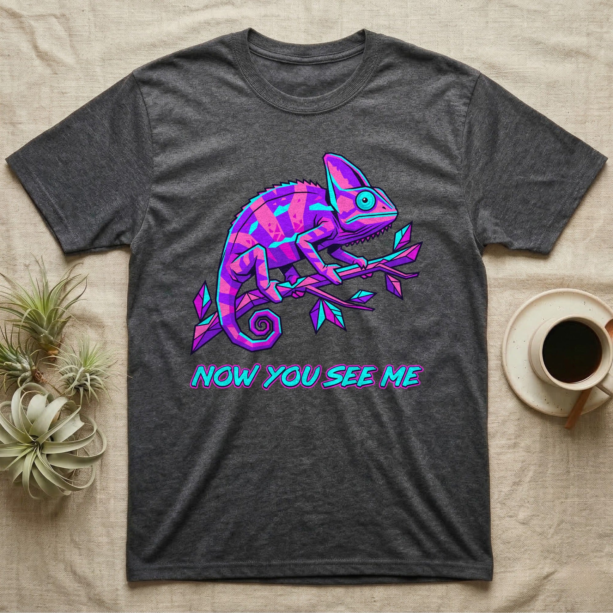 Dark t-shirt with neon purple and blue chameleon on branch, "NOW YOU SEE ME" text.