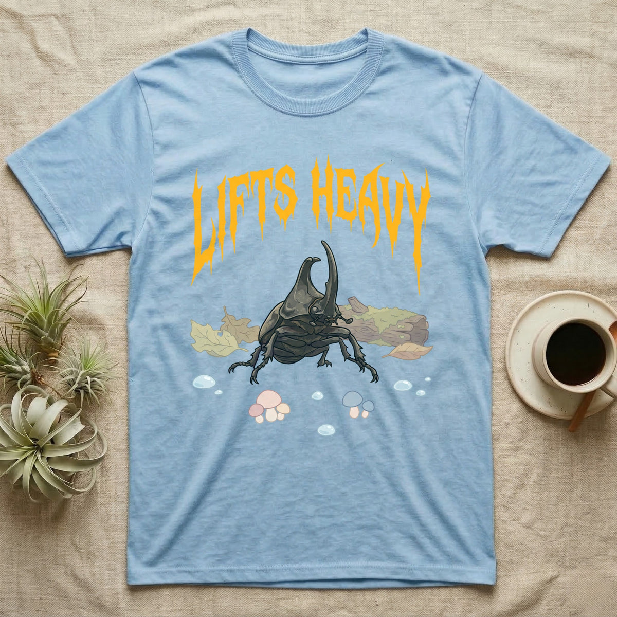 Rhino Beetle Feral T-Shirt in Light Blue — Horned rhinoceros beetle standing head-on below a dripping amber-gold metal "Lifts Heavy" wordmark