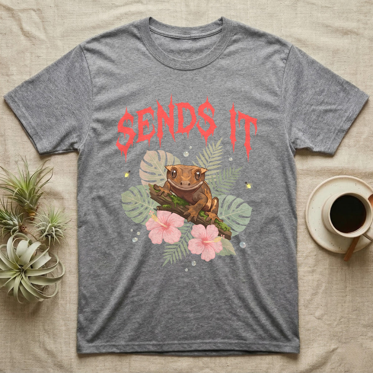Crested Gecko Feral T-Shirt in Sport Grey — Crested gecko on a mossy branch in a pastel jungle scene under a spiky coral metal wordmark reading SENDS IT.