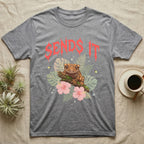 Crested Gecko Feral T-Shirt in Sport Grey — Crested gecko on a mossy branch in a pastel jungle scene under a spiky coral metal wordmark reading SENDS IT.