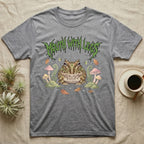 Pacman Frog Feral T-Shirt in Sport Grey — Round Pacman frog in a pastel forest-floor scene under a spiky leaf-green metal wordmark reading MOUTH WITH LEGS.