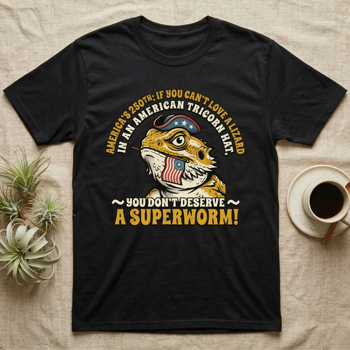 Bearded Dragon Tricorn Tee in Black — Bold woodcut tee of a bearded dragon in a colonial tricorn hat, gold and cream text reading You Don't Deserve A Superworm, on black.