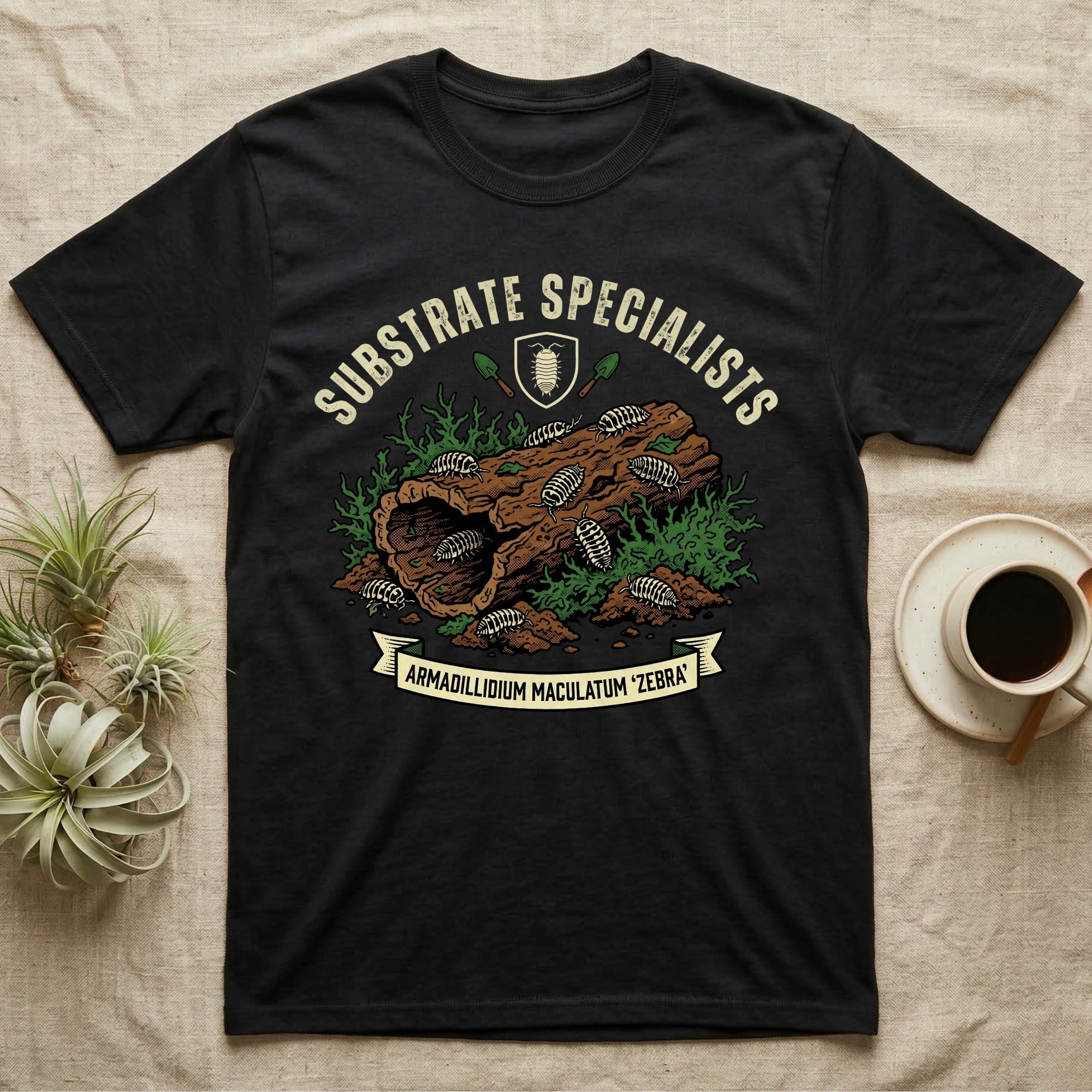 Zebra Isopod Substrate Specialists T-Shirt in Black — Vintage crest of zebra isopods on a mossy cork log with crossed trowels and Armadillidium ribbon.