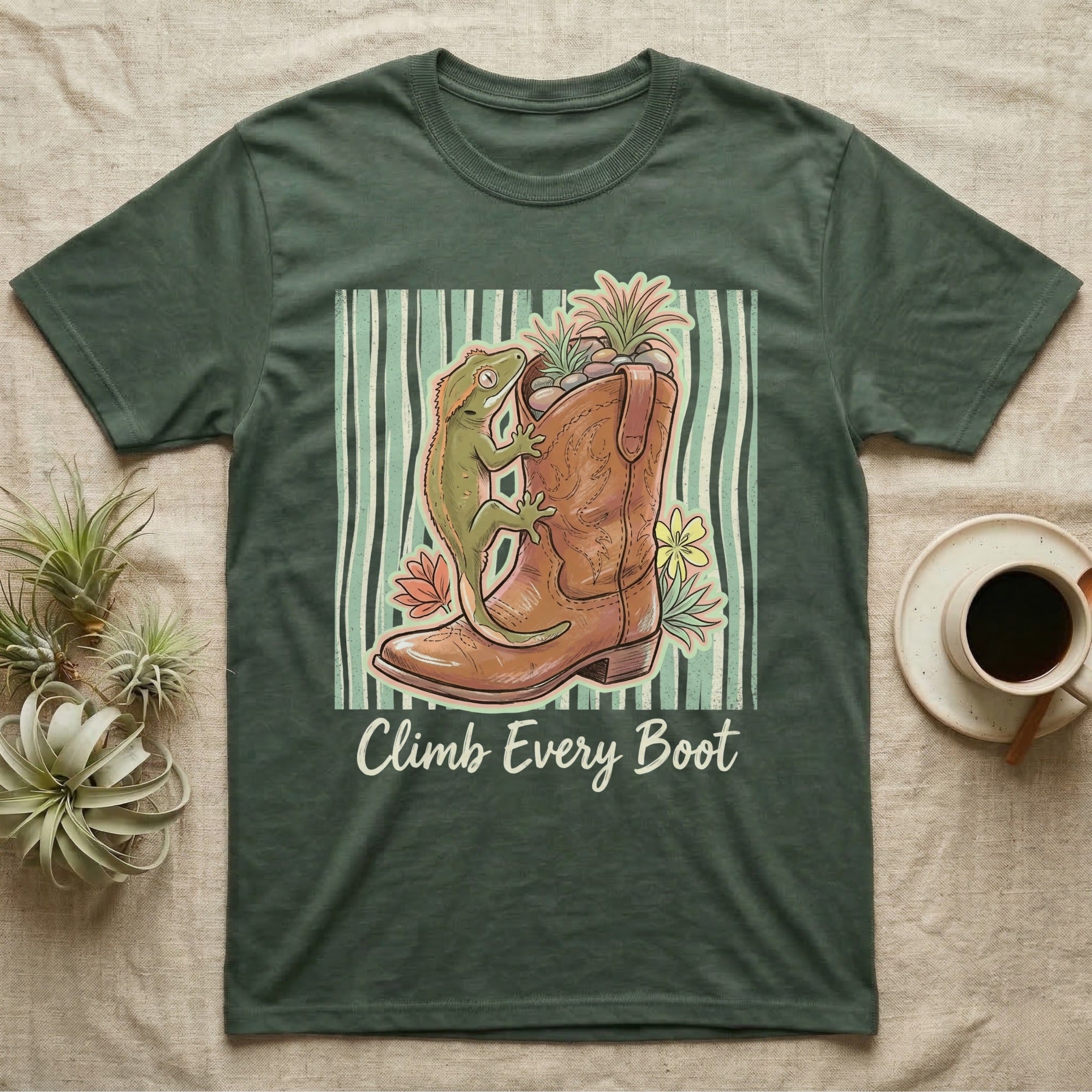 Green t-shirt with a gecko climbing a cowboy boot, surrounded by plants.