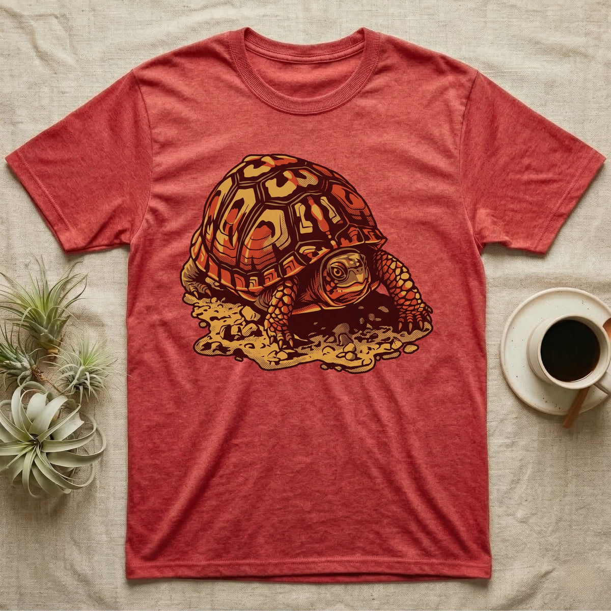 Vintage ink illustration of an Eastern box turtle crawling across sandy pebbles, high-domed shell shown in rust-red and amber, no on-shirt text. — shown on a Heather Red tee.