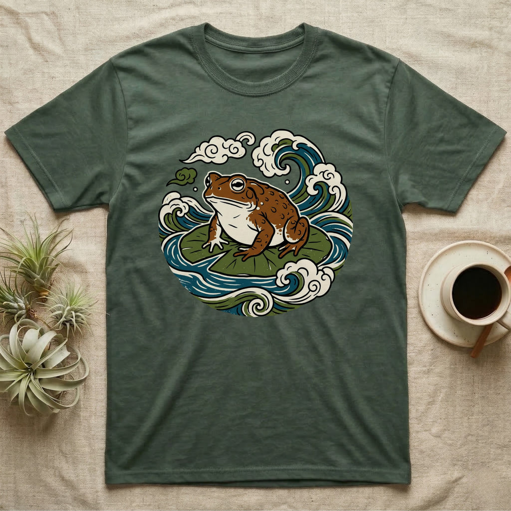 Green t-shirt with a cartoon frog sitting on lily pads with waves and clouds.