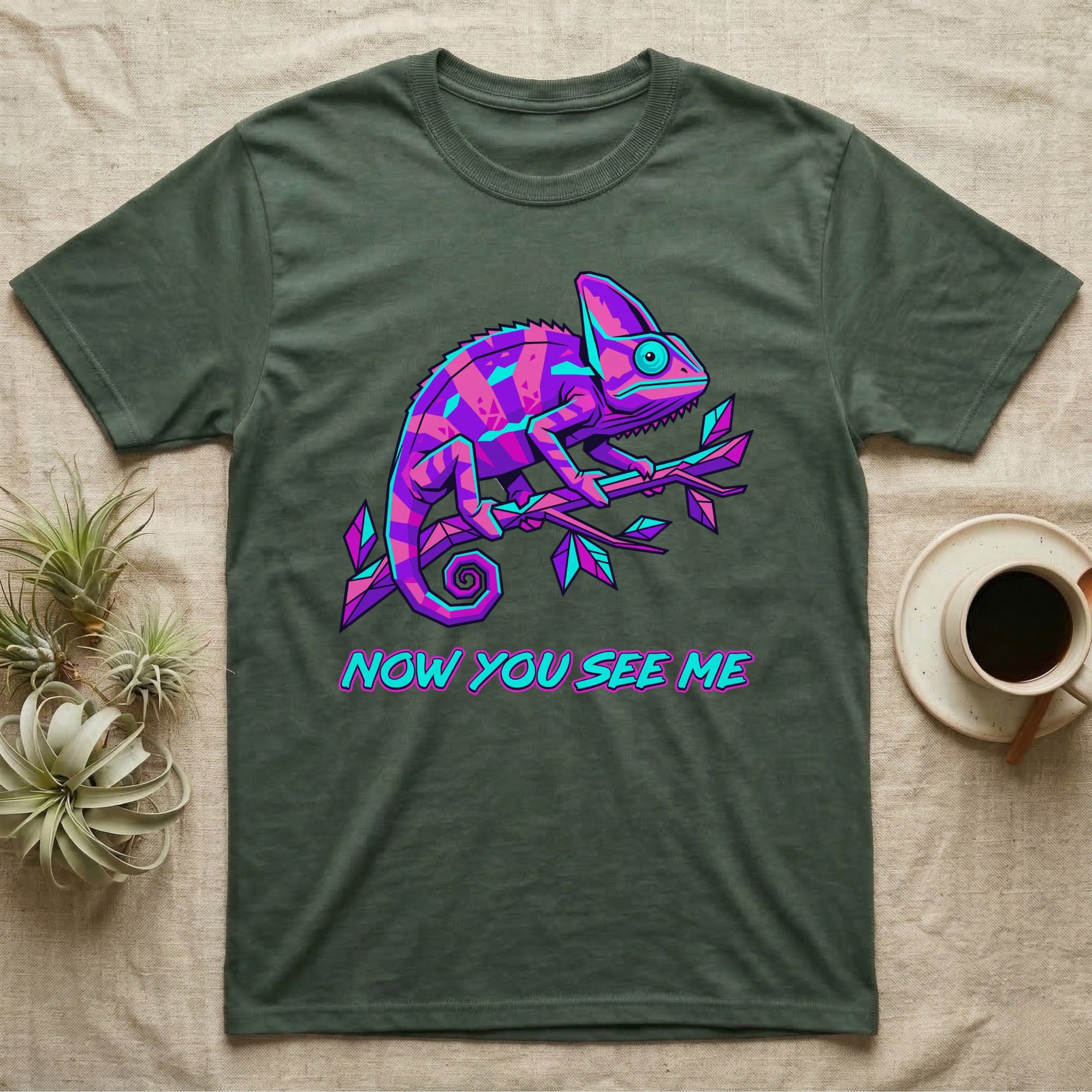 Green t-shirt with a neon pink and purple chameleon on a branch and text "NOW YOU SEE ME".
