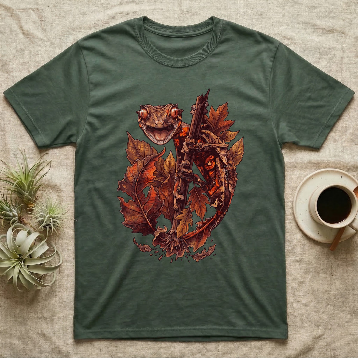 Satanic Leaf-Tailed Gecko Autumn T-Shirt in Military Green — Painted illustration of a satanic leaf-tailed gecko gripping a bare stem among dried autumn leaves in rust and amber, no on-shirt text.