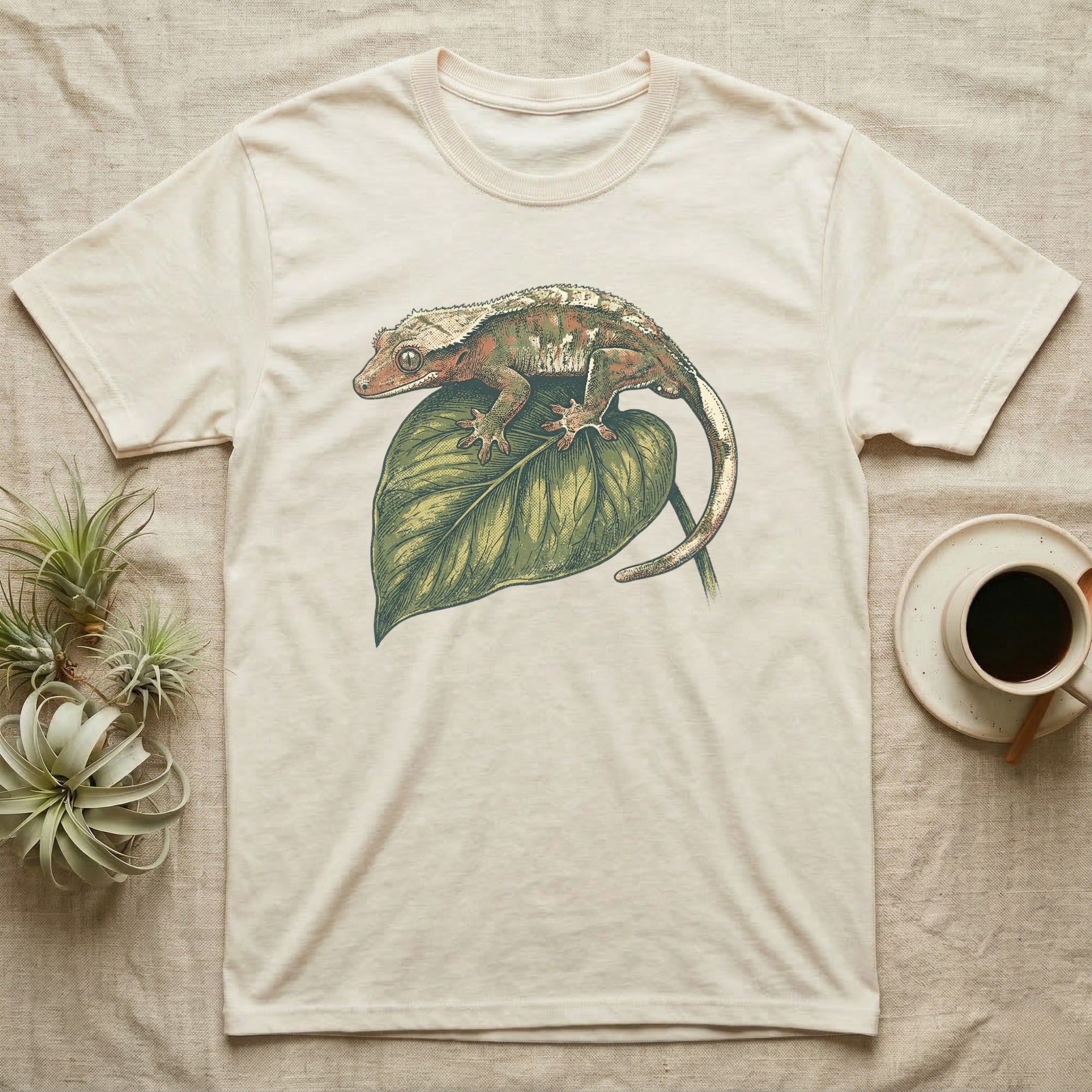 Cream t-shirt with a gecko on a green leaf graphic.