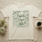 Reptile Expo T-Shirt in Natural — Green marker cursive reading Reptile Expo just looking, ringed by doodles of deli cups, tubs, a gecko and a tortoise