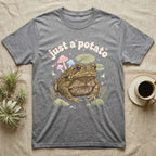 Cane Toad Baby T-Shirt in Sport Grey — Warty cane toad among pastel toadstools and lily pads under puffy cream bubble text "just a potato".
