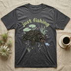 Alligator Snapping Turtle Softie T-Shirt in Dark Heather — Alligator snapping turtle with open mouth and tongue lure under a puffy pastel "just fishing" bubble wordmark.