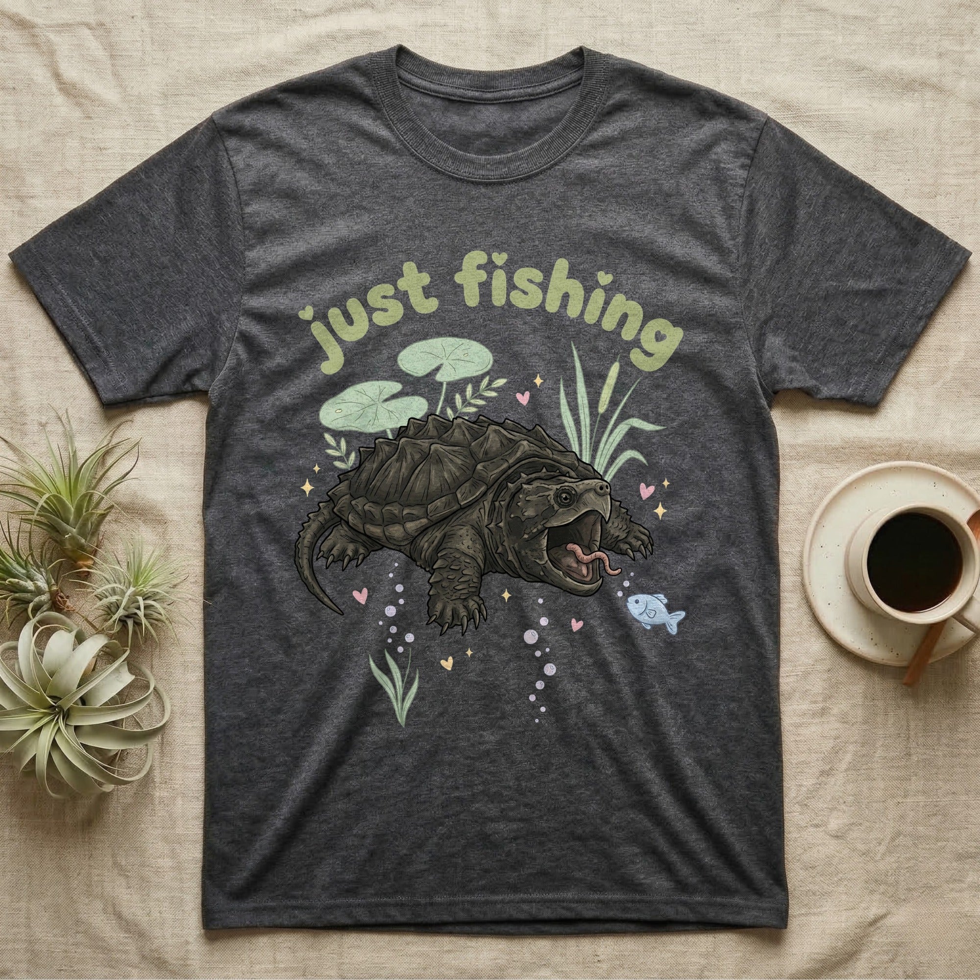 Alligator Snapping Turtle Softie T-Shirt in Dark Heather — Alligator snapping turtle with open mouth and tongue lure under a puffy pastel "just fishing" bubble wordmark.