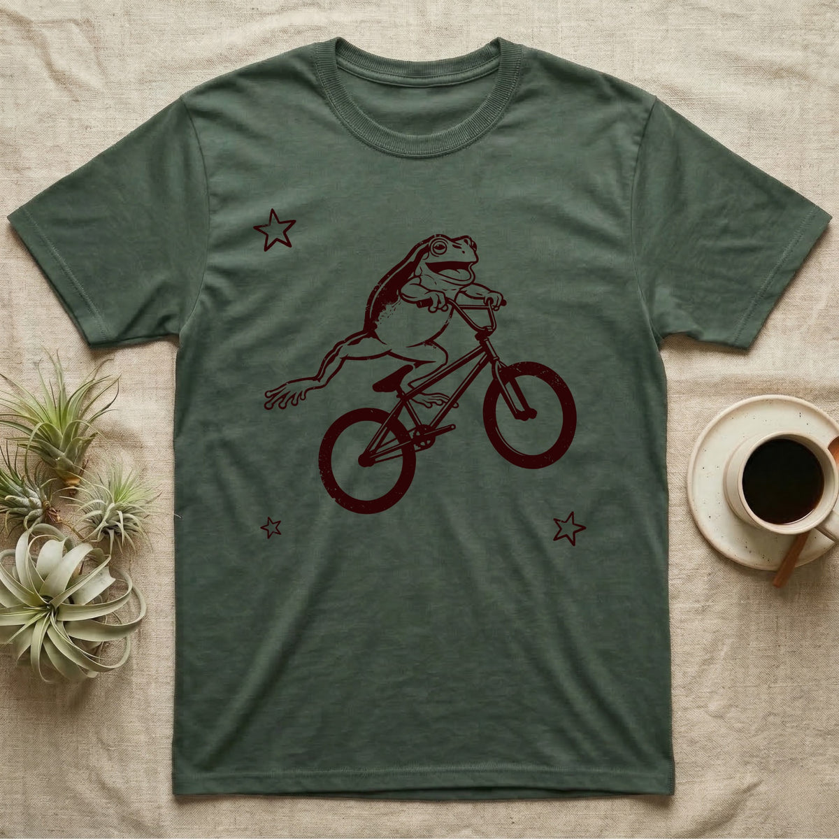Tree Frog Can-Can T-Shirt in Military Green — Distressed one-ink oxblood screenprint of a White's tree frog airborne on a BMX bike, both back legs kicked off the pedals and swung to one side, hands still on the bars.
