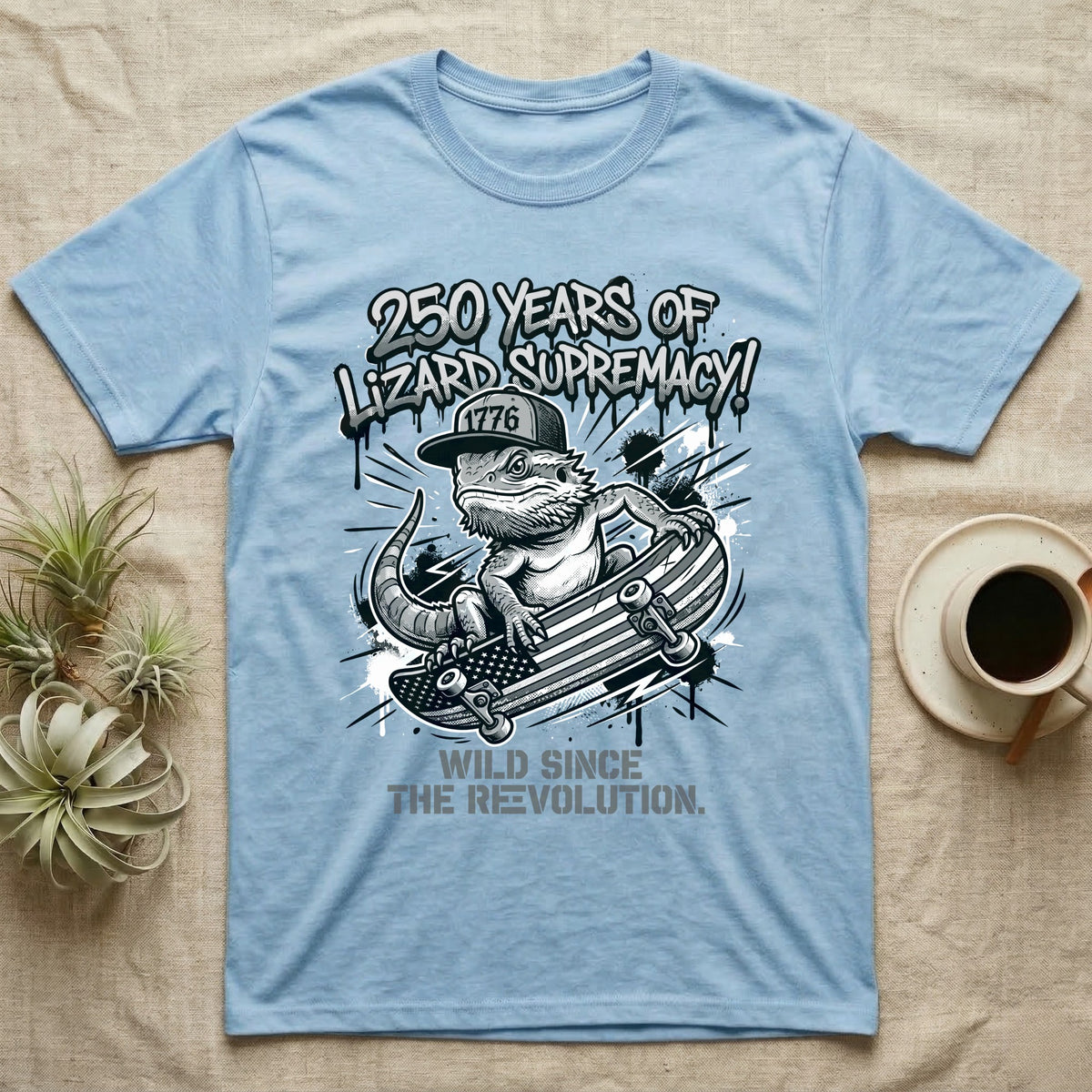 Bearded Dragon Skater T-Shirt in Light Blue — Black-and-white bearded dragon in a 1776 snapback on a flag skateboard under text 250 Years of Lizard Supremacy.