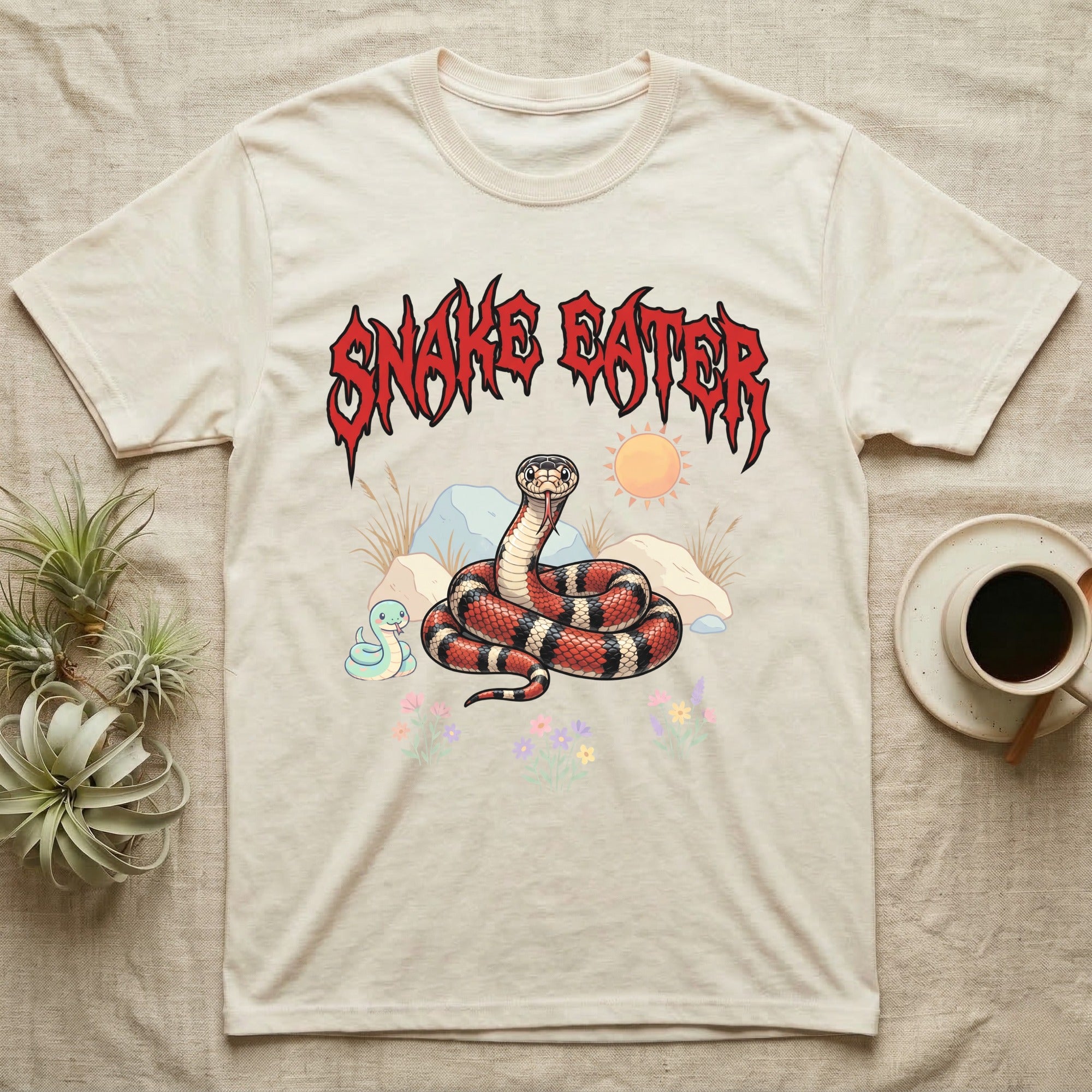 California Kingsnake Feral T-Shirt in Natural — Banded California kingsnake coiled with a tiny companion snake under a jagged blood-red metal wordmark and pastel scene.