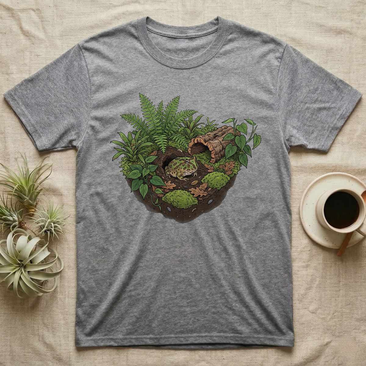 Pacman Frog Vivarium T-Shirt in Sport Grey — Botanical illustration of a pacman frog thriving in a planted bioactive vivarium beside a small empty plastic cup.