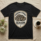 Ball Python Feeding Strike T-Shirt in Black — Vintage-ink badge of a coiled ball python with carved type "Feeding Strike Season" and fine print "Months 3-7 Of Every Year."