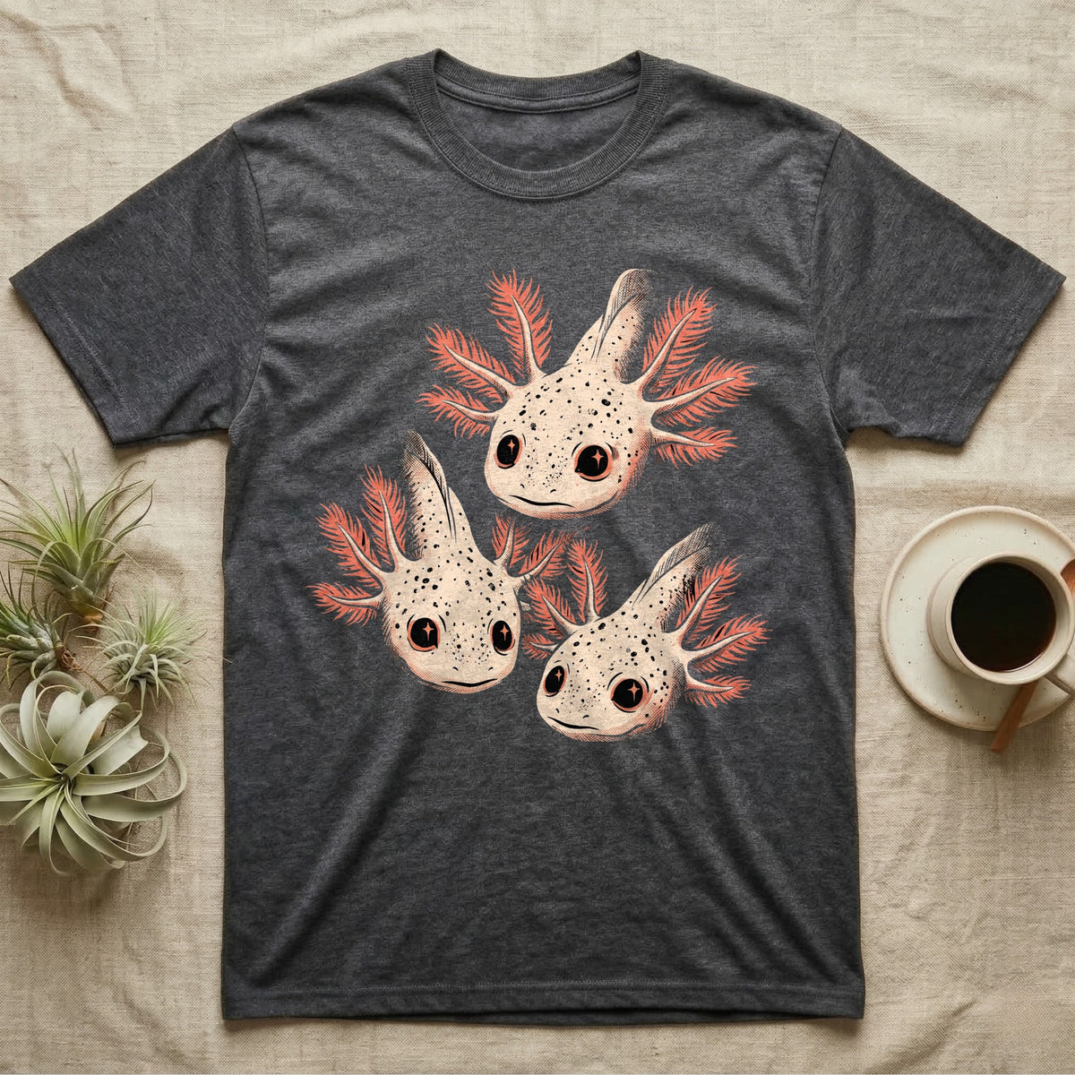 Vintage comic screen-print illustration of three axolotls clustered together with coral feathery gills and sparkling star-highlighted eyes, graphic-only, no text. — shown on a Dark Heather tee.