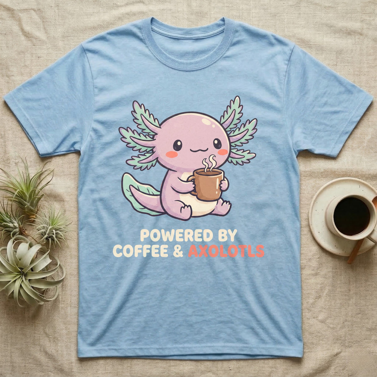 Coffee And Axolotls T-Shirt in Light Blue — Kawaii chibi illustration of an axolotl holding a coffee cup with soft text reading Powered By Coffee And Axolotls.