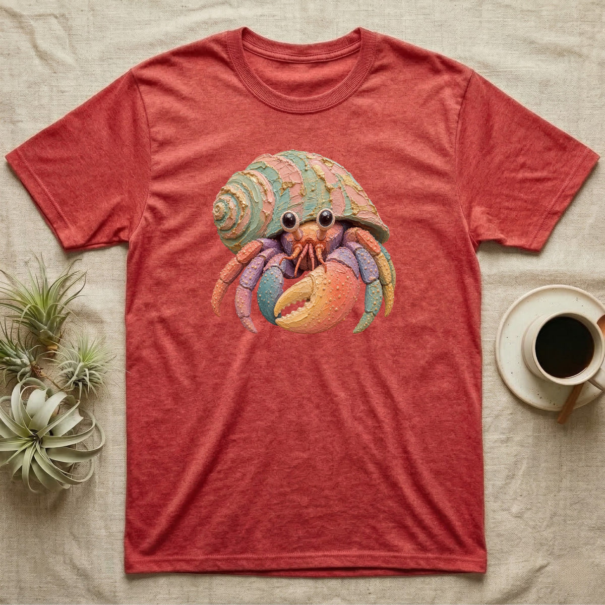 Red t-shirt with colorful hermit crab graphic and textured background.