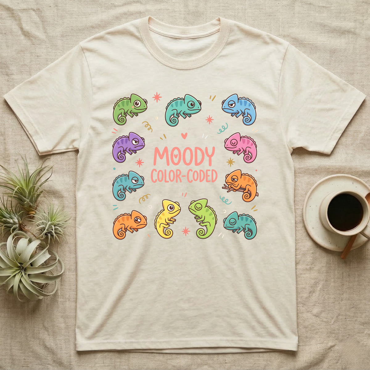Chameleon Moody T-Shirt in Natural — Ten cartoon chameleons in different colours and moods around the coral-pink words MOODY COLOR-CODED