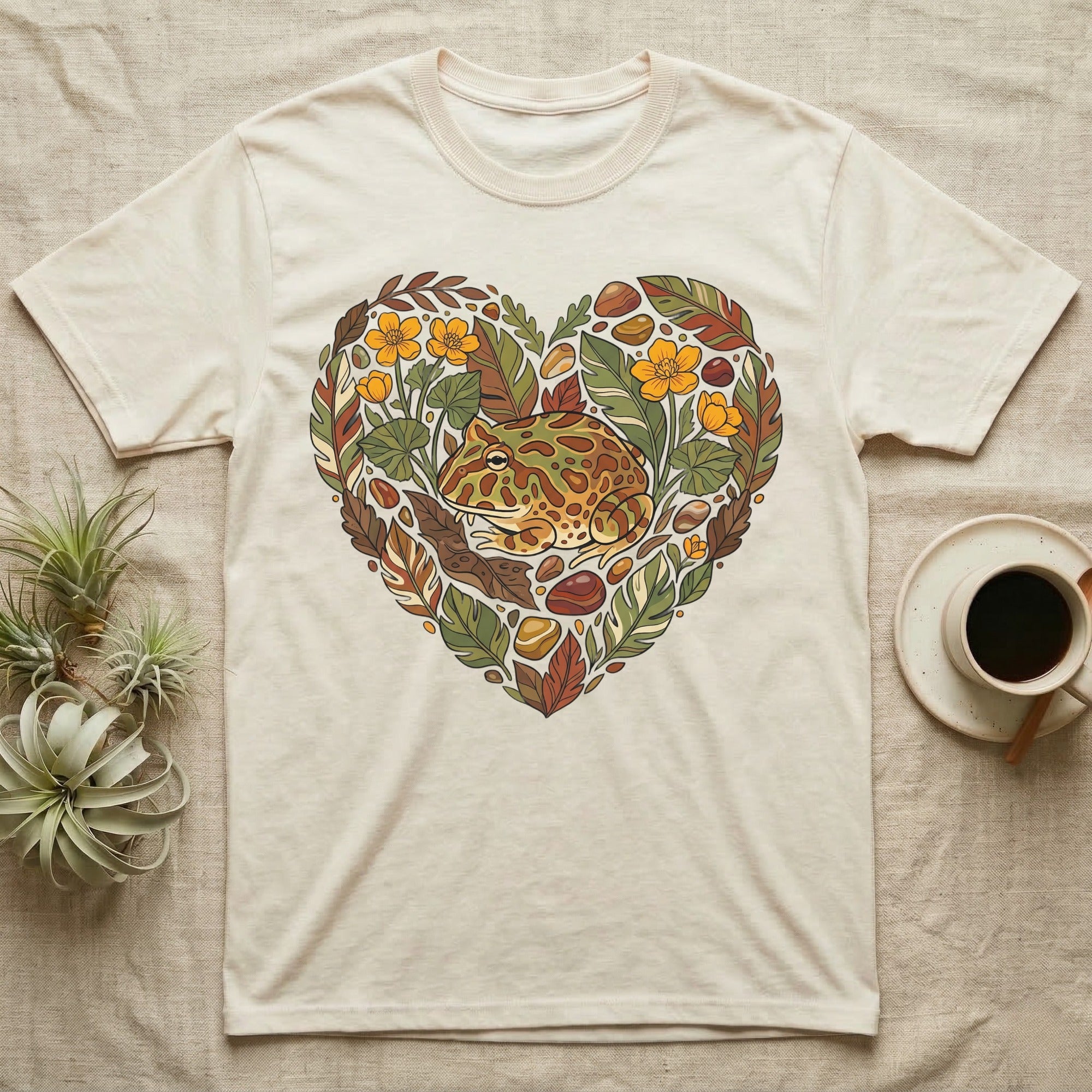 Cream t-shirt with heart-shaped floral and frog graphic.