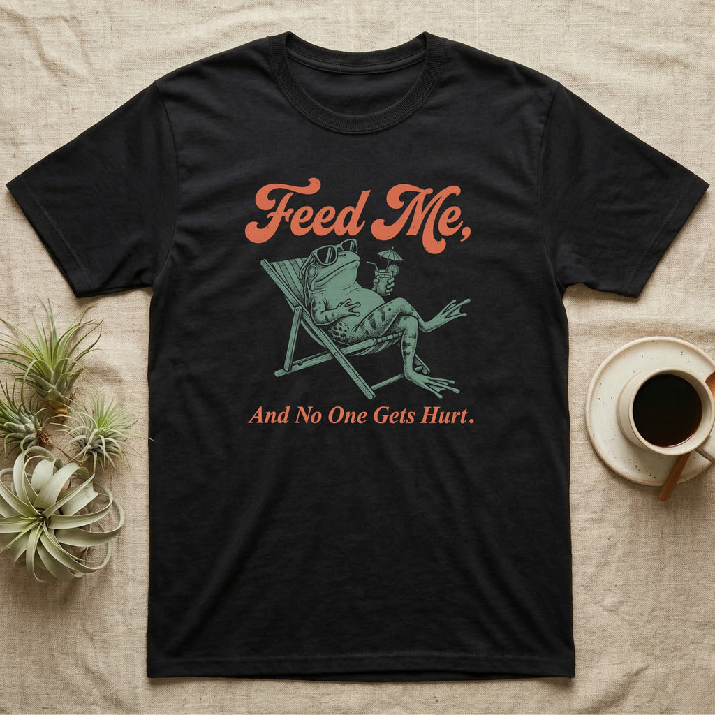 American Bullfrog Beach Chair T-Shirt in Black — Illustrated American bullfrog lounging in a beach chair with sunglasses and a tropical drink, coral script reading Feed Me And No One Gets Hurt.